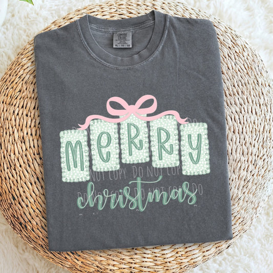 Gray t-shirt with 'Merry Christmas' design on a woven mat