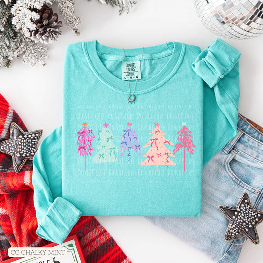 Turquoise sweatshirt with Christmas tree design on a white surface with festive decorations.