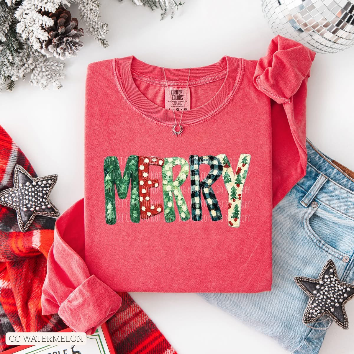 Red shirt with 'MERRY' text on a white surface with Christmas decorations