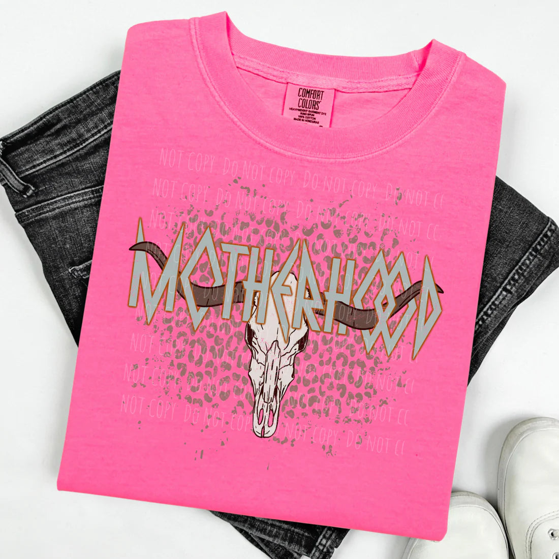 Pink t-shirt with graphic design and text, displayed with jeans and sneakers on a white background