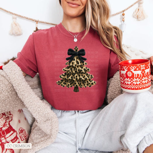 Person wearing a red sweatshirt with a Christmas tree design, holding a mug with a festive pattern.