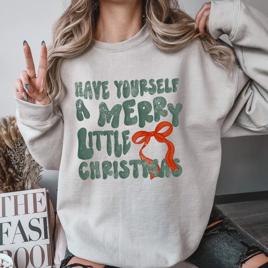 Person wearing a light gray sweatshirt with Christmas-themed text and design.