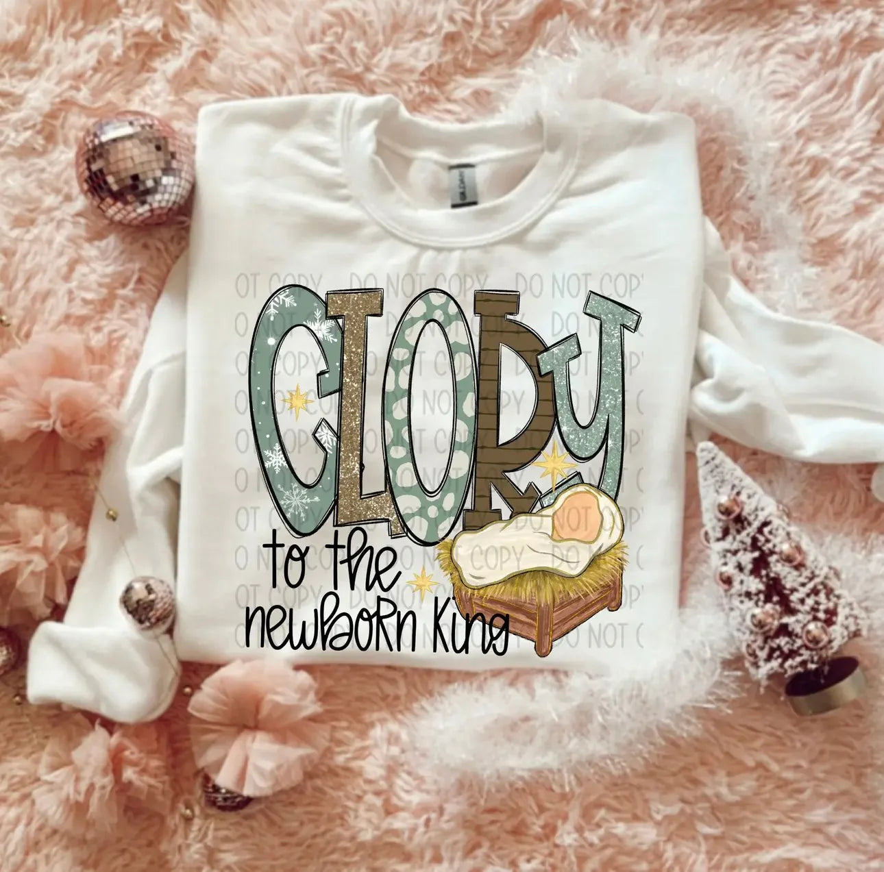 White sweatshirt with 'GLORY to the newborn King' text on a pink fluffy background