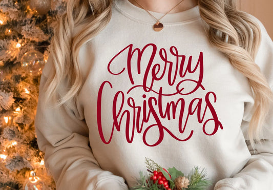 Person wearing a white sweatshirt with 'Merry Christmas' in red text, standing in front of a decorated Christmas tree.